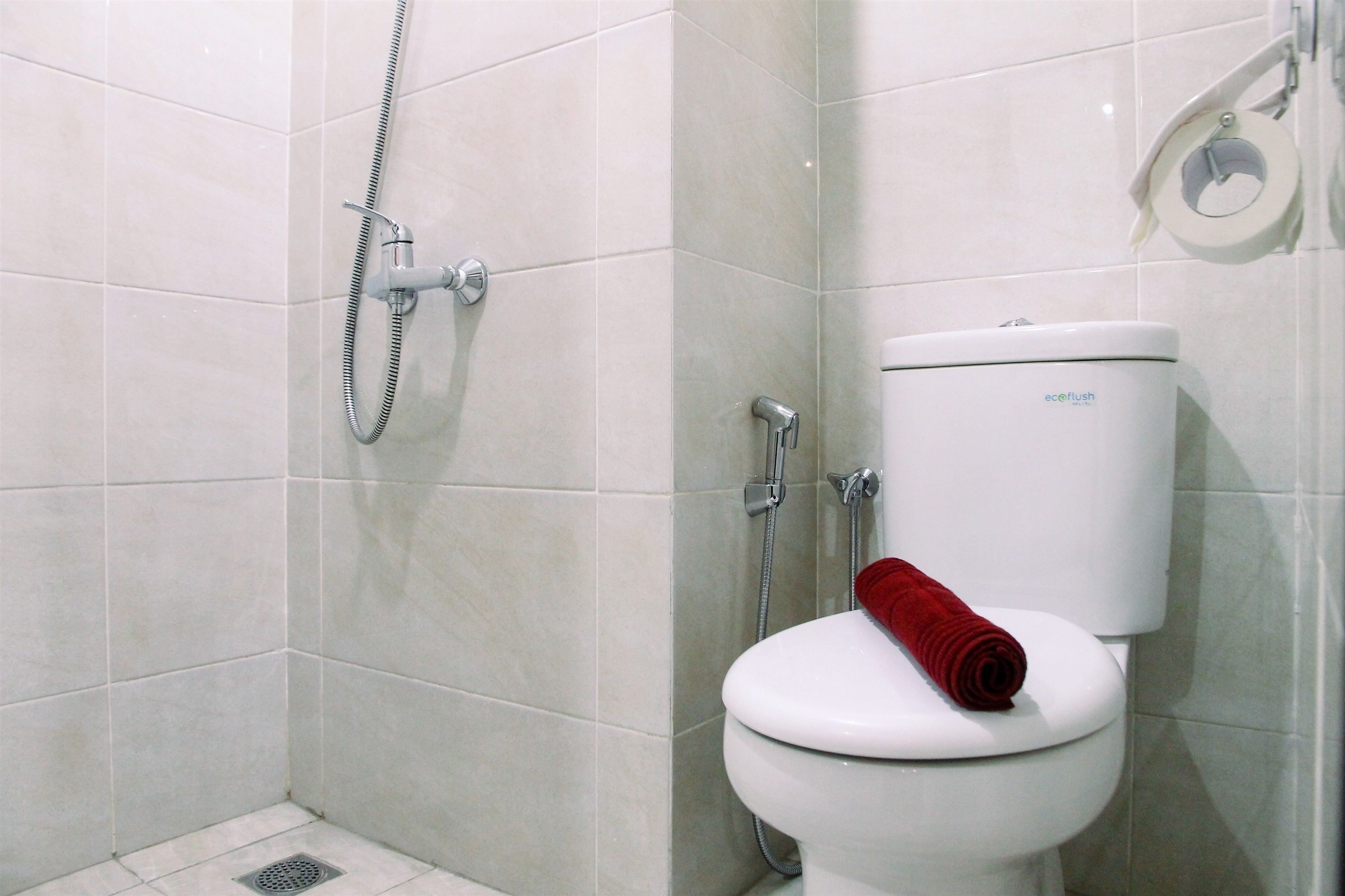Une salle de bain équipée de toilettes, d’une douche et d’un porte-rouleau de papier toilette.