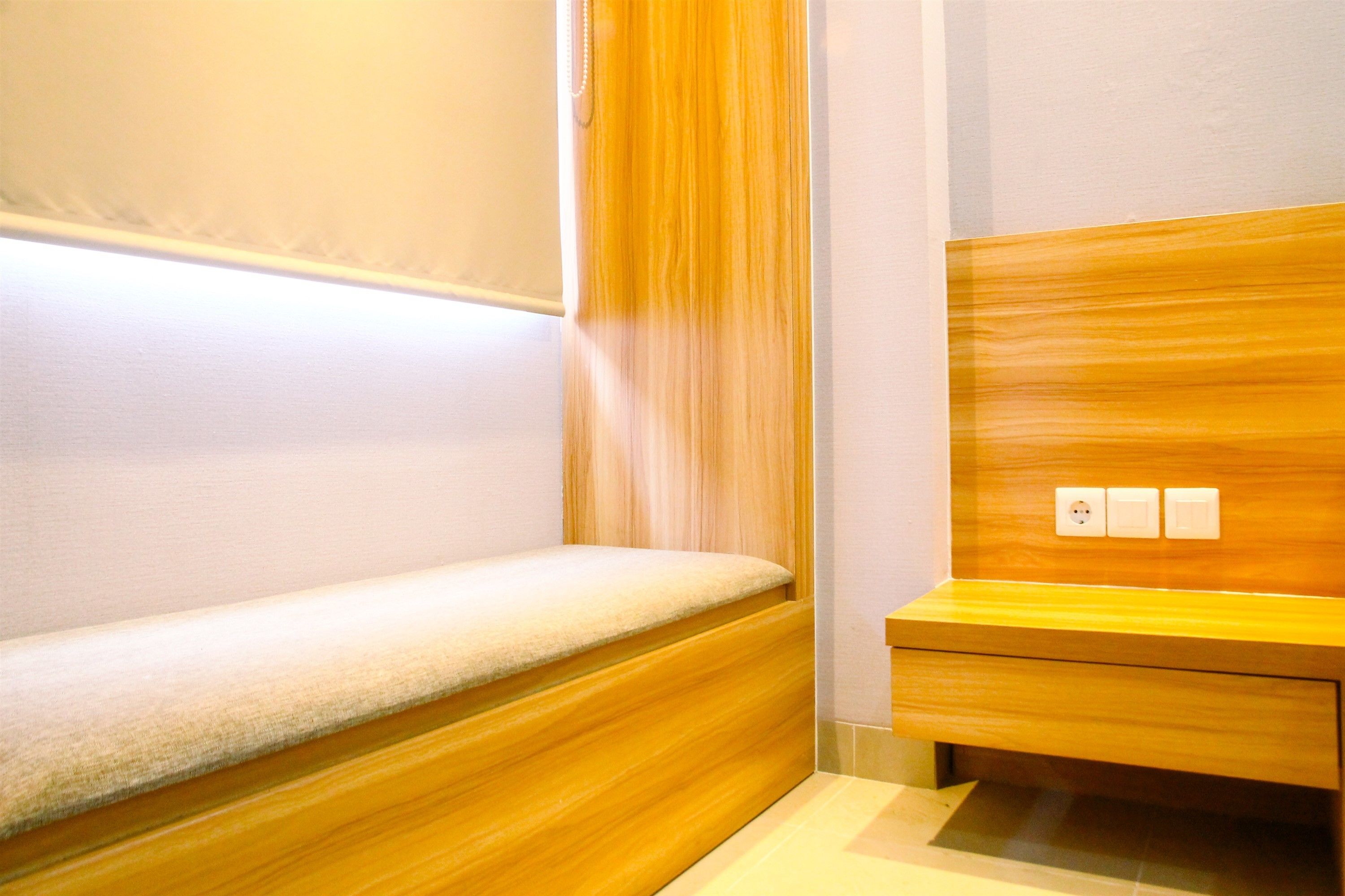 Une salle de bain moderne avec un meuble-lavabo en bois, un banc et un luminaire fixé au mur.