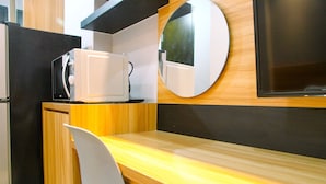 A compact kitchenette with a microwave, a small refrigerator, and a wooden countertop. - Modern and Comfy Studio @ Mustika Golf Apartment (Cikarang)