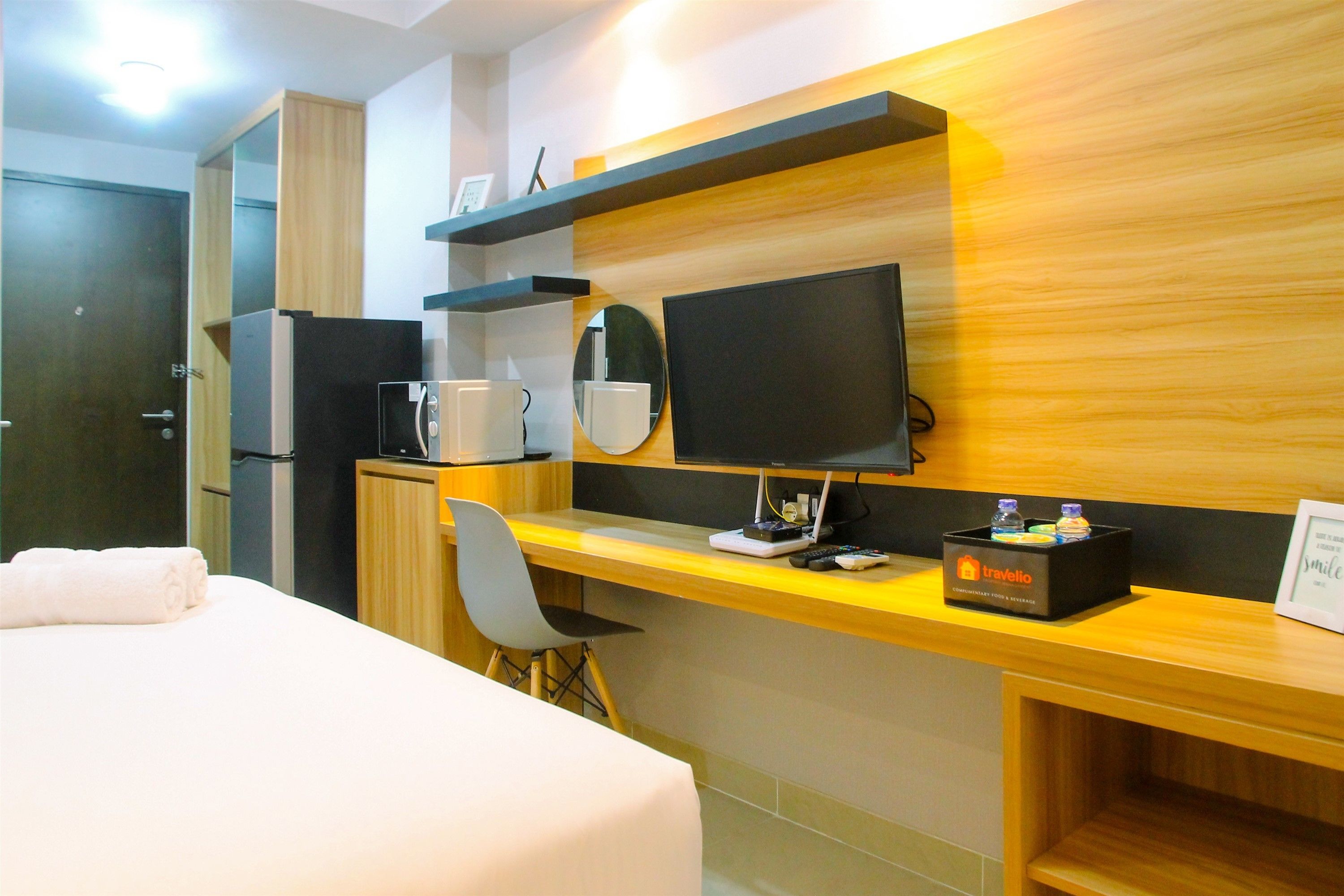 Een hotelkamer met een bed, een bureau met een computer, een televisie en een minibar.