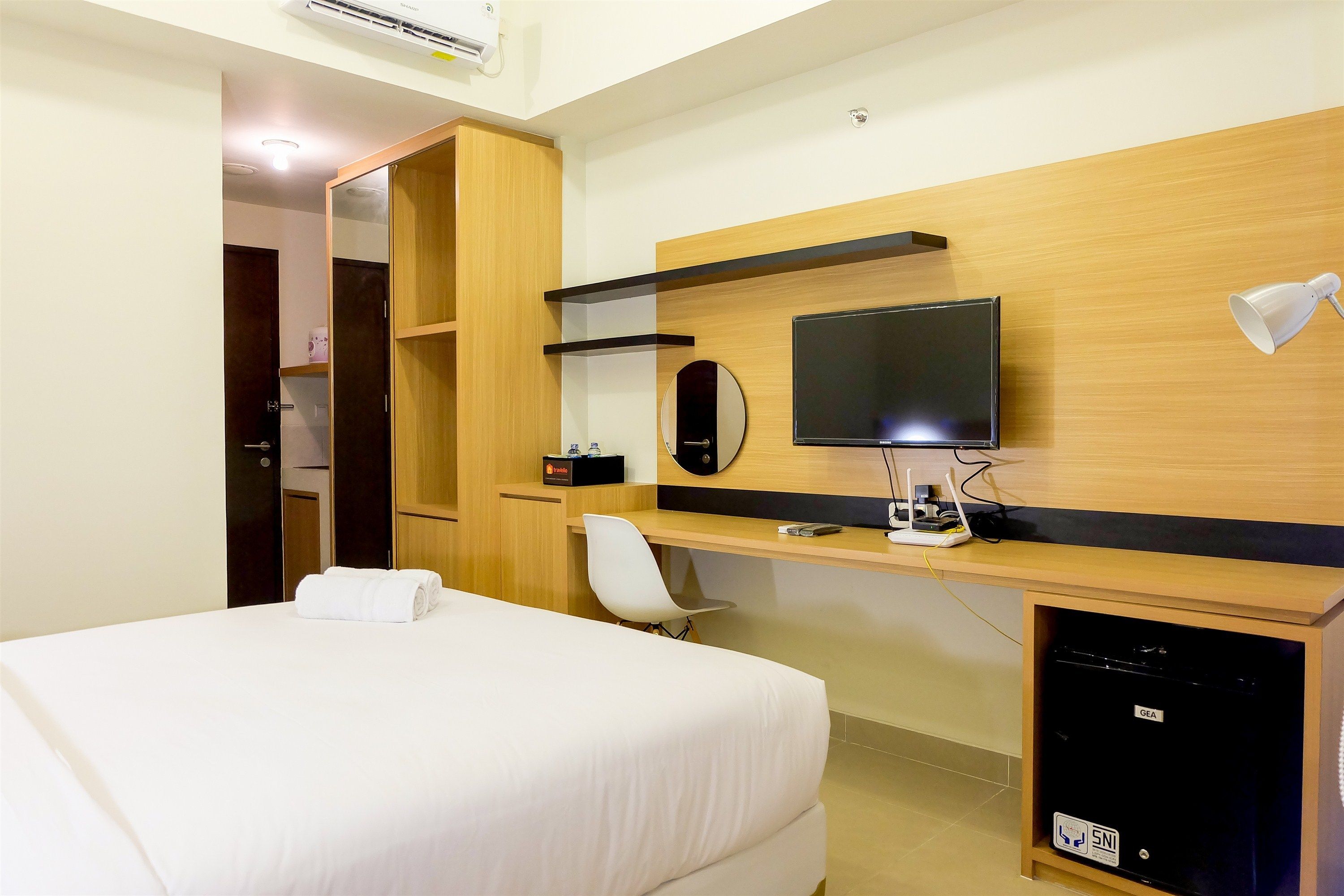 Ein Hotelzimmer mit Bett, Schreibtisch mit Computer, Fernseher und einer Minibar.