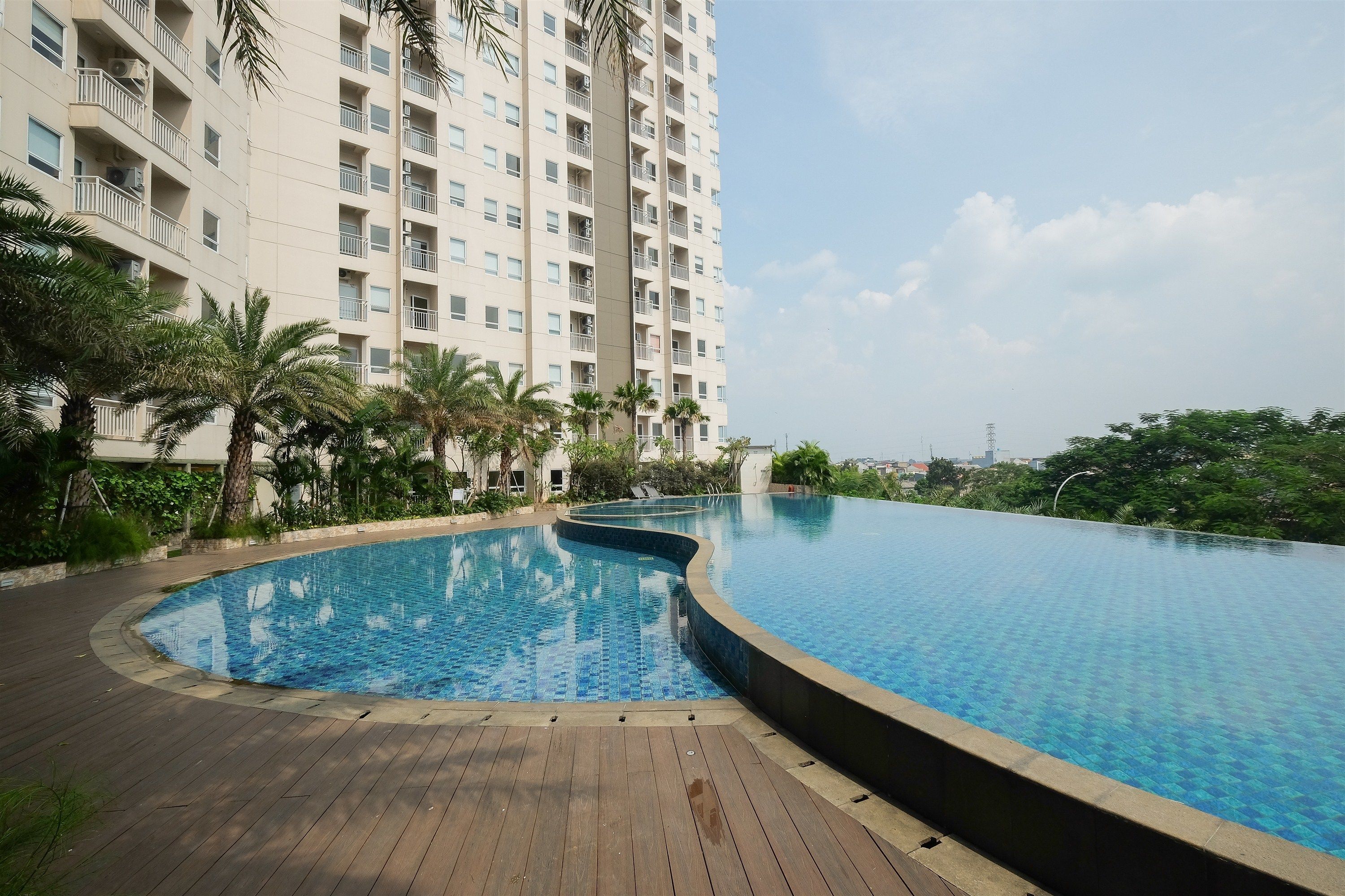 Un moderno edificio de gran altura con piscina y palmeras.