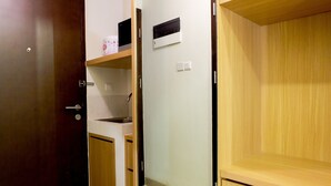 A room with a wooden door, a white wall, and a wooden cabinet. - Comfy Studio Mustika Golf Apartment (Cikarang)