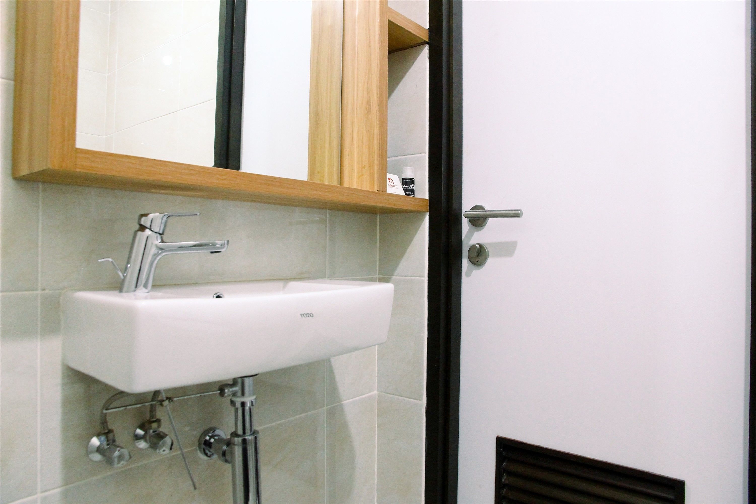 Un baño con un lavamanos blanco, un espejo y un mueble de madera sobre el lavamanos.