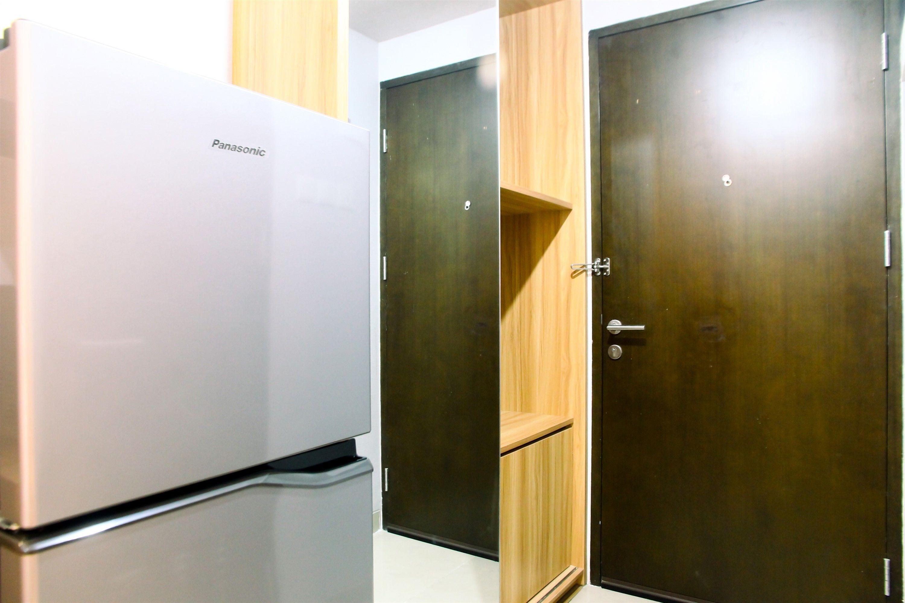 Un frigorifero bianco Panasonic e due porte in legno in una stanza.