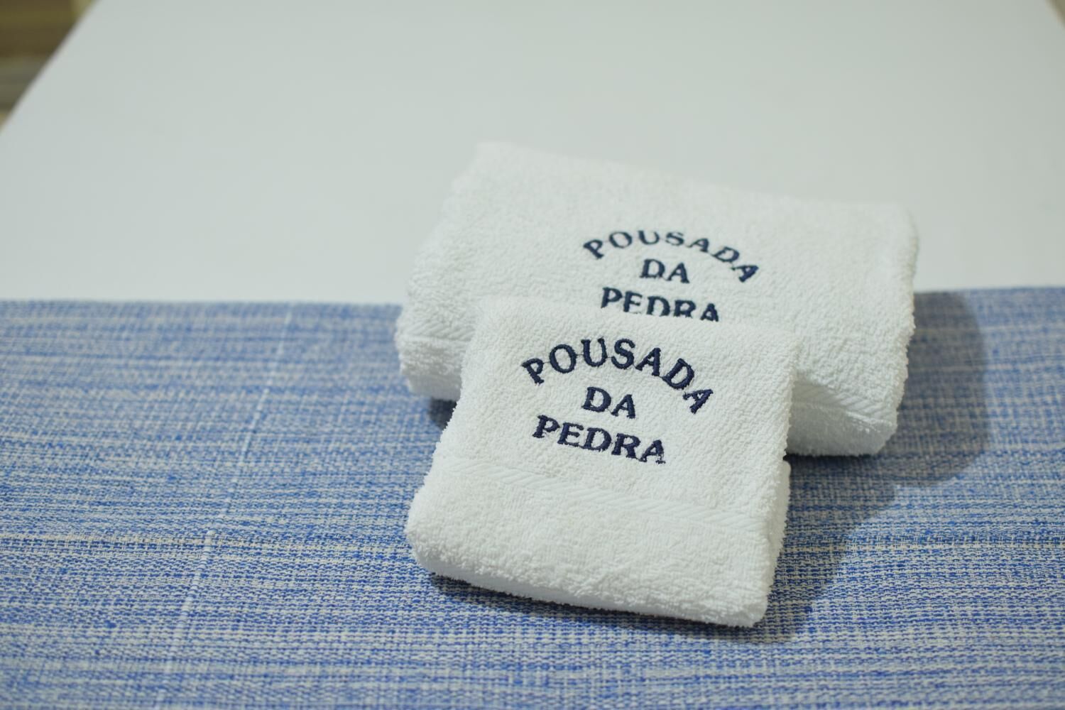 Two white towels with text on them placed on a blue fabric surface.