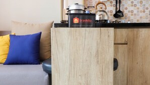 Een kitchenette met een koelkast voor eten en drinken met travelio branding, een waterkoker en een pan op het aanrecht.