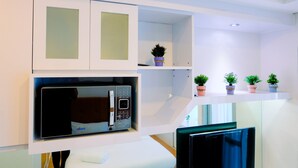A modern kitchen with a built-in microwave, a small potted plant, and a shelf with multiple potted plants.