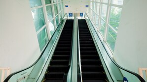 Eine Rolltreppe mit Glaswänden und Hinweisschildern.