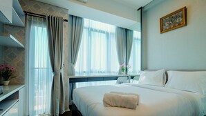 Ein Hotelzimmer mit einem großen Bett, einem Schreibtisch und einem Fenster mit Vorhängen.