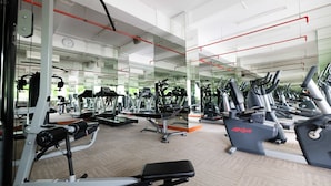 Ein Fitnessstudio mit verschiedenen Trainingsgeräten, Spiegeln und einem Teppichboden.