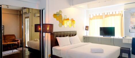 Ein modernes Hotelzimmer mit einem großen Bett, einem Schreibtisch, einem Fernseher und einem Spiegel.