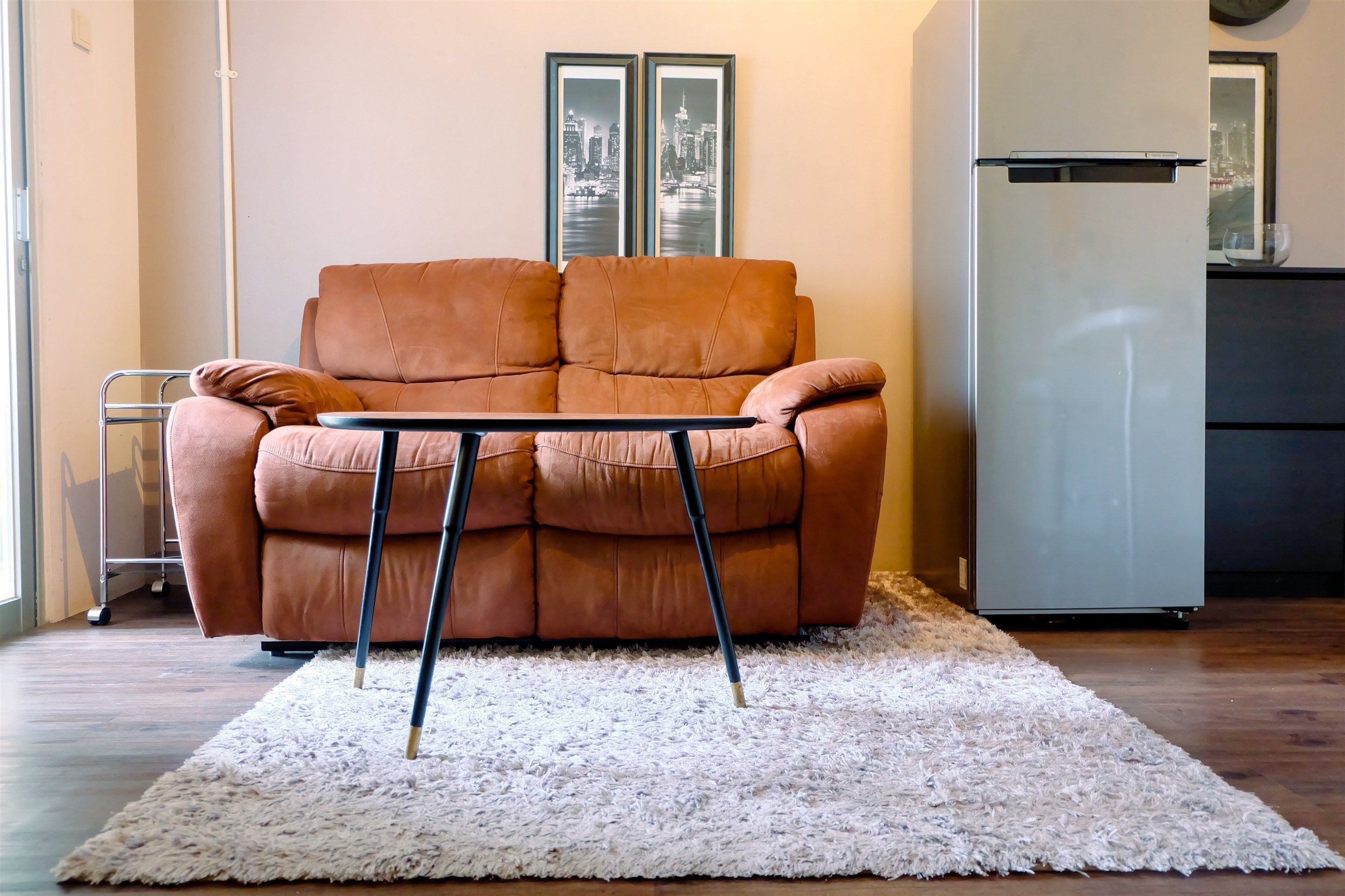A living room with a brown sofa, a white shag rug, and a small table.