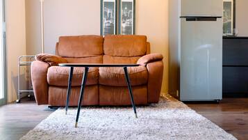 A living room with a brown sofa, a white shag rug, and a small table.