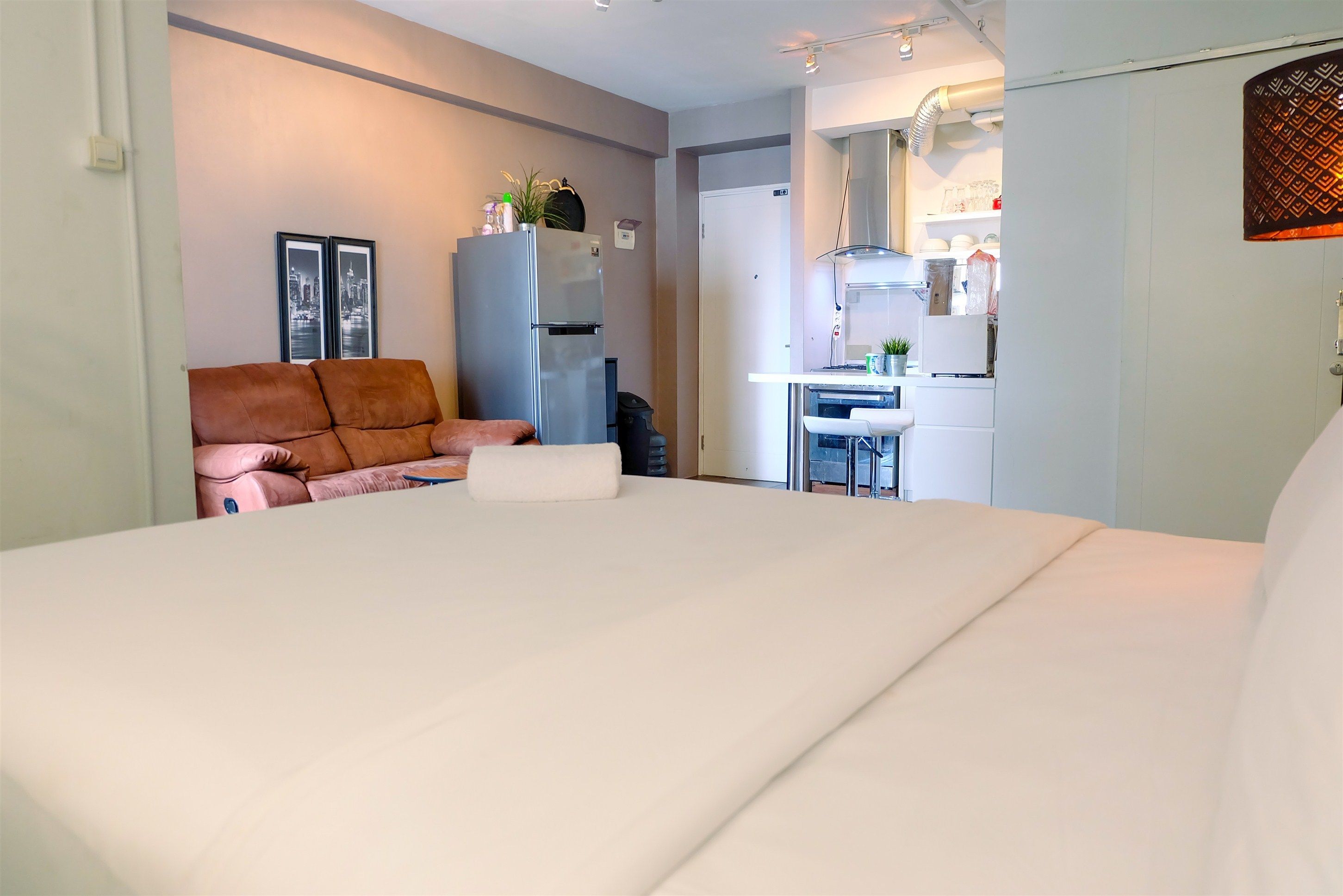 Ein Schlafzimmer mit einem großen Bett, einer Couch, einem Kühlschrank und einer Küchenzeile.