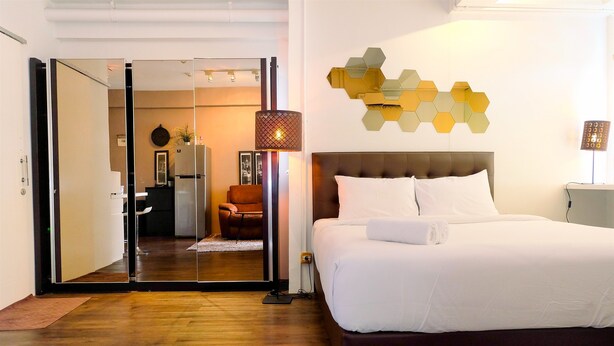 Ein modernes Hotelzimmer mit einem großen Bett, einer Glastür zu einem Wohnbereich und einem dekorativen Wandbild.