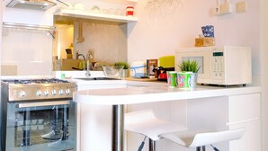 Eine moderne Küche mit Gasherd, Backofen, weißen Schränken, einer Mikrowelle und einer Bar mit Sitzgelegenheiten.