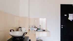 Een keuken met een fornuis, een spoelbak en een zwarte deur.