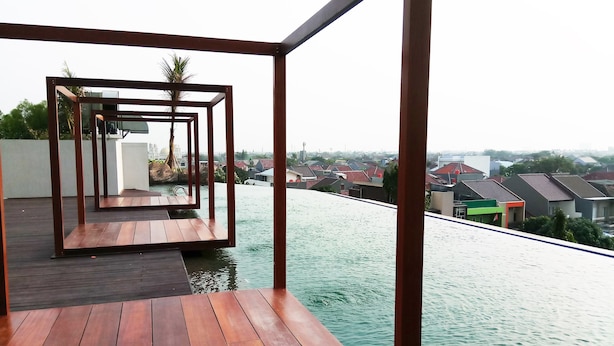 A wooden deck with a view of a residential area and a body of water. - Fabulous Studio Grand Kamala Lagoon Apartment (Bekasi)