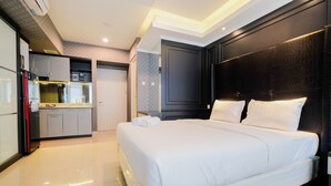 A modern hotel room with a large bed, a built-in wardrobe, a kitchenette, and a bathroom. - Fabulous Studio Grand Kamala Lagoon Apartment (Bekasi)