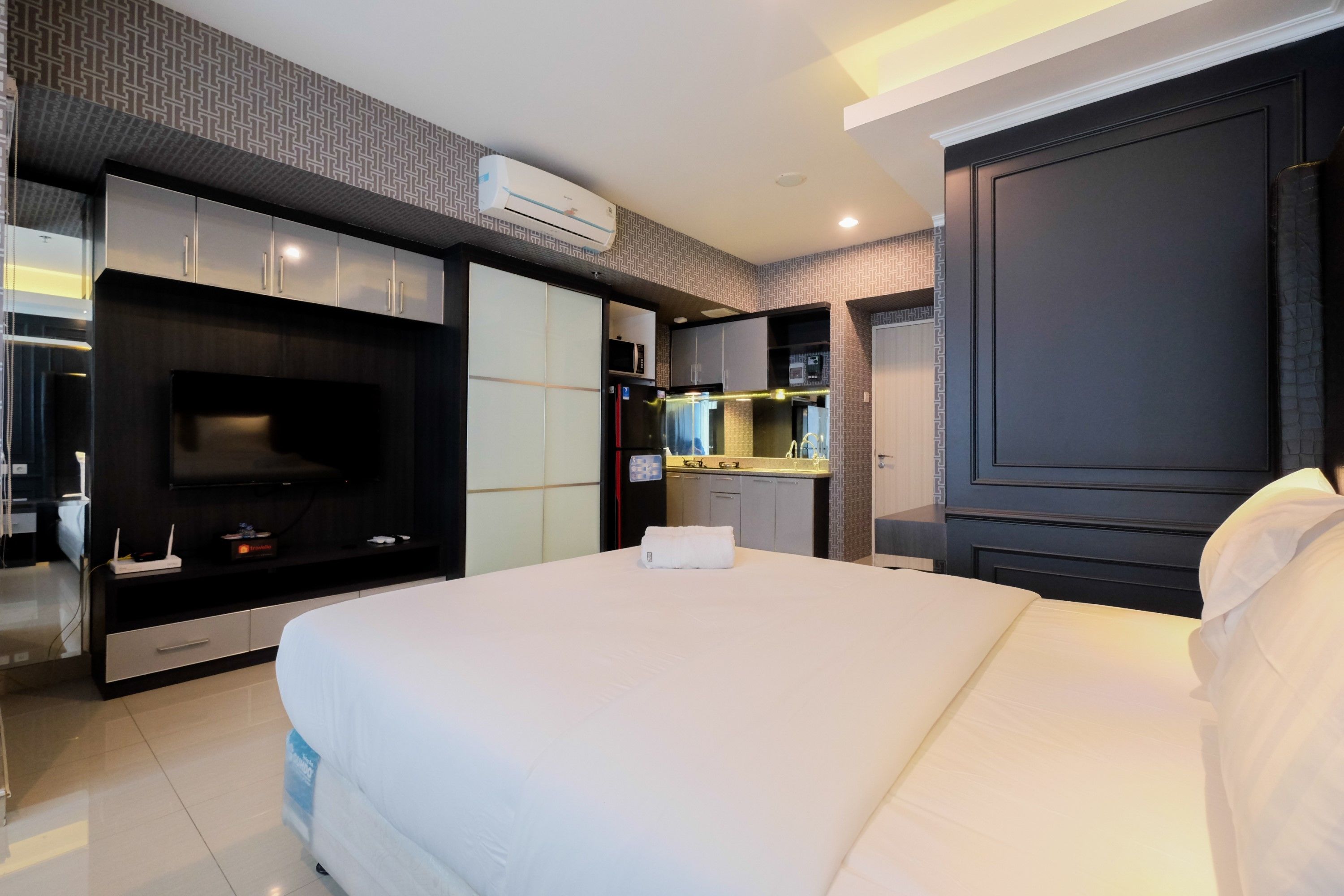 Une chambre d’hôtel moderne dotée d’un grand lit, d’une télévision intégrée, d’un minibar et d’une petite kitchenette.