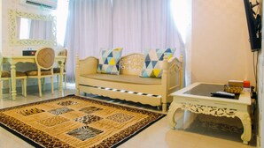 A living room with a sofa, chairs, a coffee table, and a patterned rug. - Luxury Furnished 2BR Grand Kamala Lagoon Apartment (Bekasi)