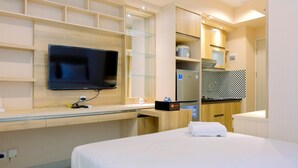 Una habitación de hotel con cama, televisión, minibar y kitchenette.