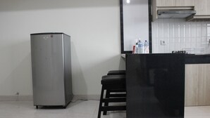 A kitchen with a stainless steel refrigerator, a black countertop, and a tiled backsplash. - Cozy 2BR Apartment @ Newton Residence (Bandung)