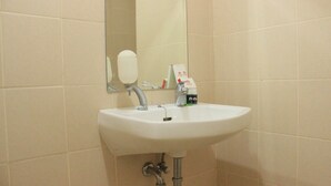 Un lavabo de salle de bain avec un miroir, un distributeur de savon et des articles de toilette.