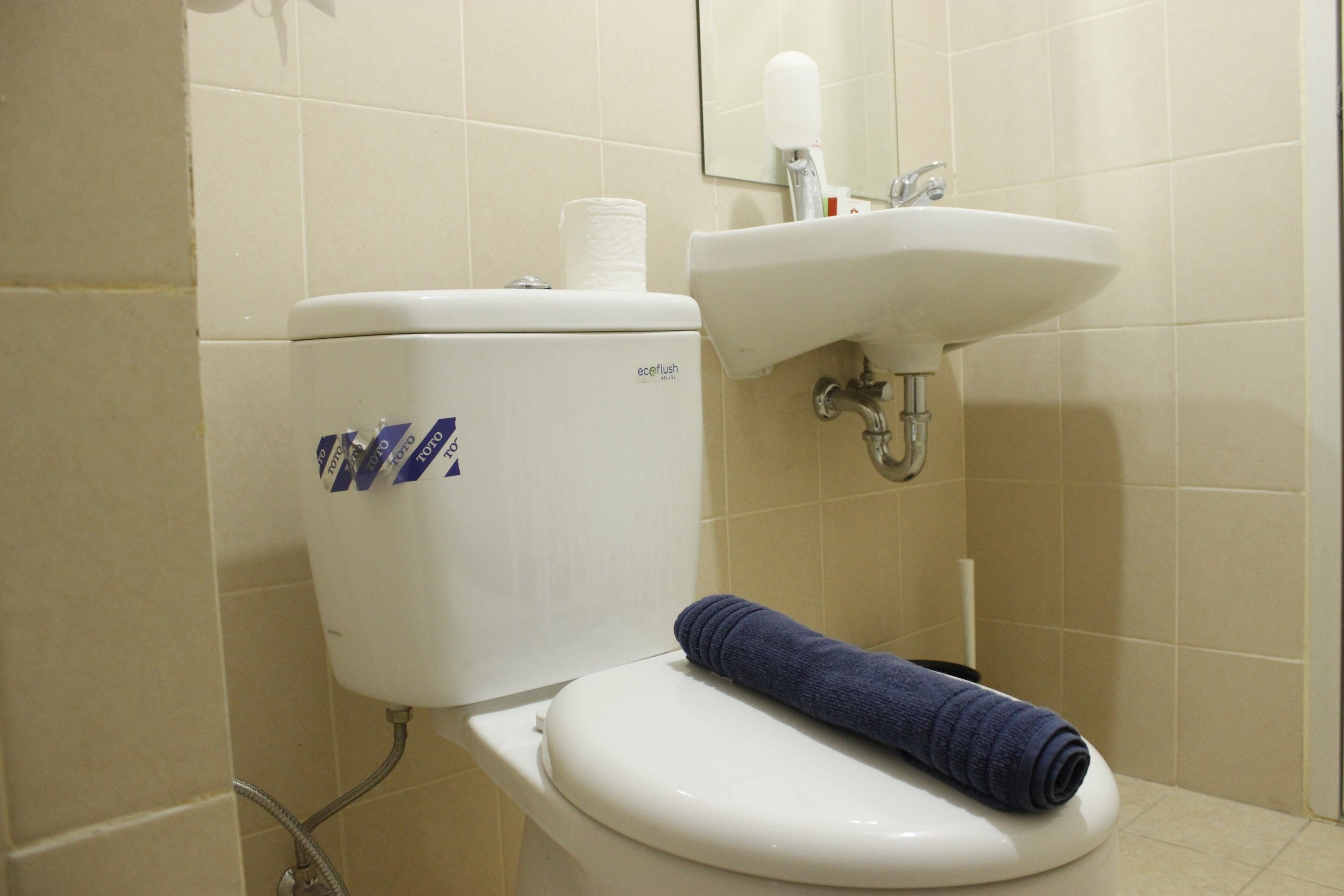 Ein Badezimmer mit Toilette, Waschbecken und einem Handtuch auf dem Toilettensitz.