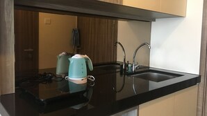 A modern kitchen with a black countertop, stainless steel sink, and two electric kettles. - Strategic Studio Galeri Ciumbuleuit 3 Apartment near Dago (Bandung)