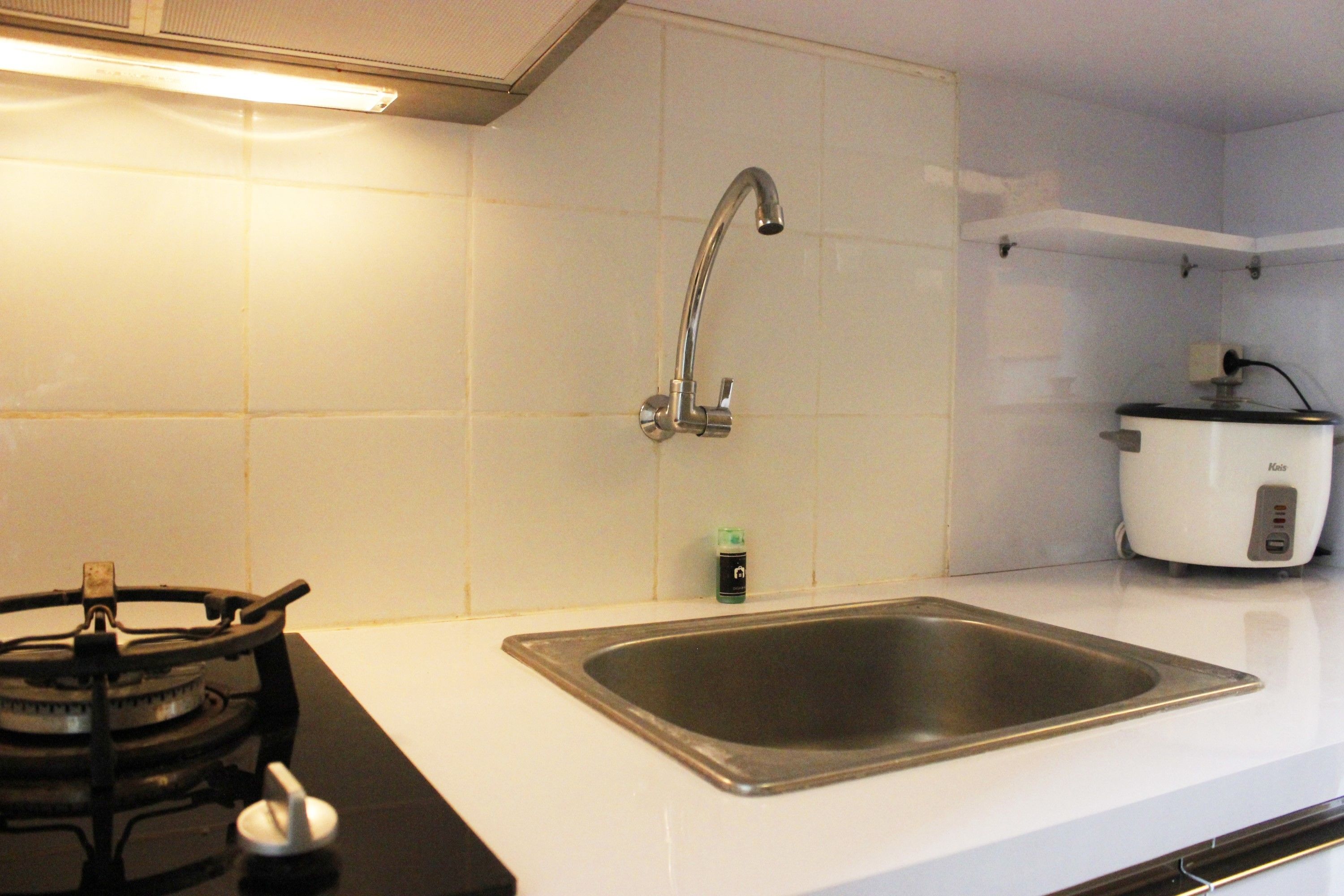 A kitchen with a gas stove, stainless steel sink, and a rice cooker.