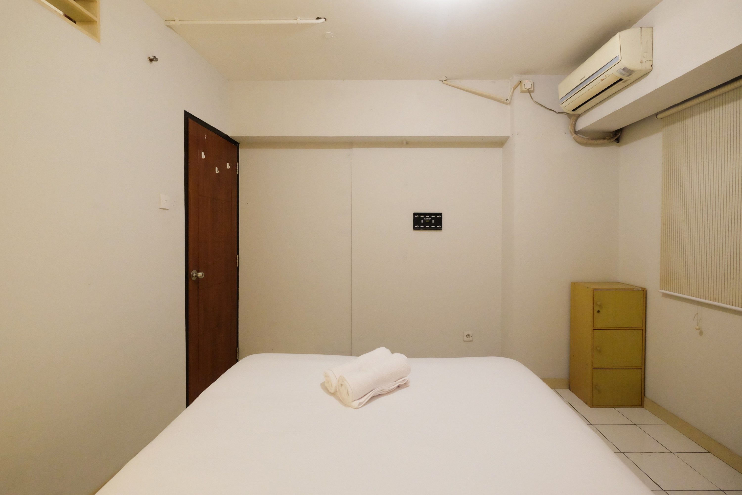 Un dormitorio con cama, un armario de madera y un equipo de aire acondicionado.