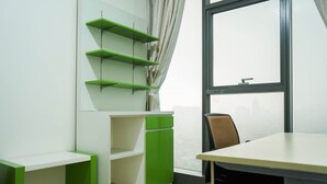 Un espacio de oficina moderno con un escritorio blanco, estanterías verdes y un amplio ventanal.