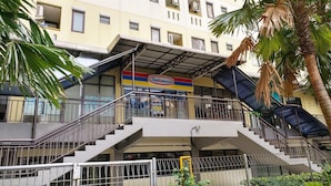 A multi-story building with a prominent Indomaret sign, outdoor staircases, and a palm tree. - Minimalist Studio at Kebagusan City Apartment (Jakarta)