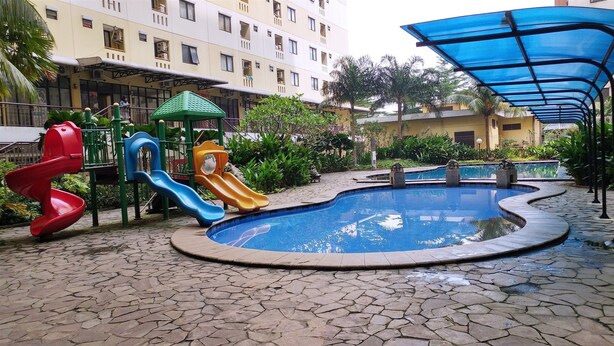 A playground with slides and a small pool, surrounded by a paved area and residential buildings. - Minimalist Studio at Kebagusan City Apartment (Jakarta)