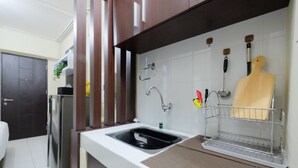 A kitchen with a stainless steel refrigerator, a sink, and a wooden cutting board on a rack. - Minimalist Studio at Kebagusan City Apartment (Jakarta)