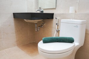 A bathroom with a white toilet, a black sink, and a mirror above the sink. - South Tower 2BR at L'Avenue Apartment (Jakarta)