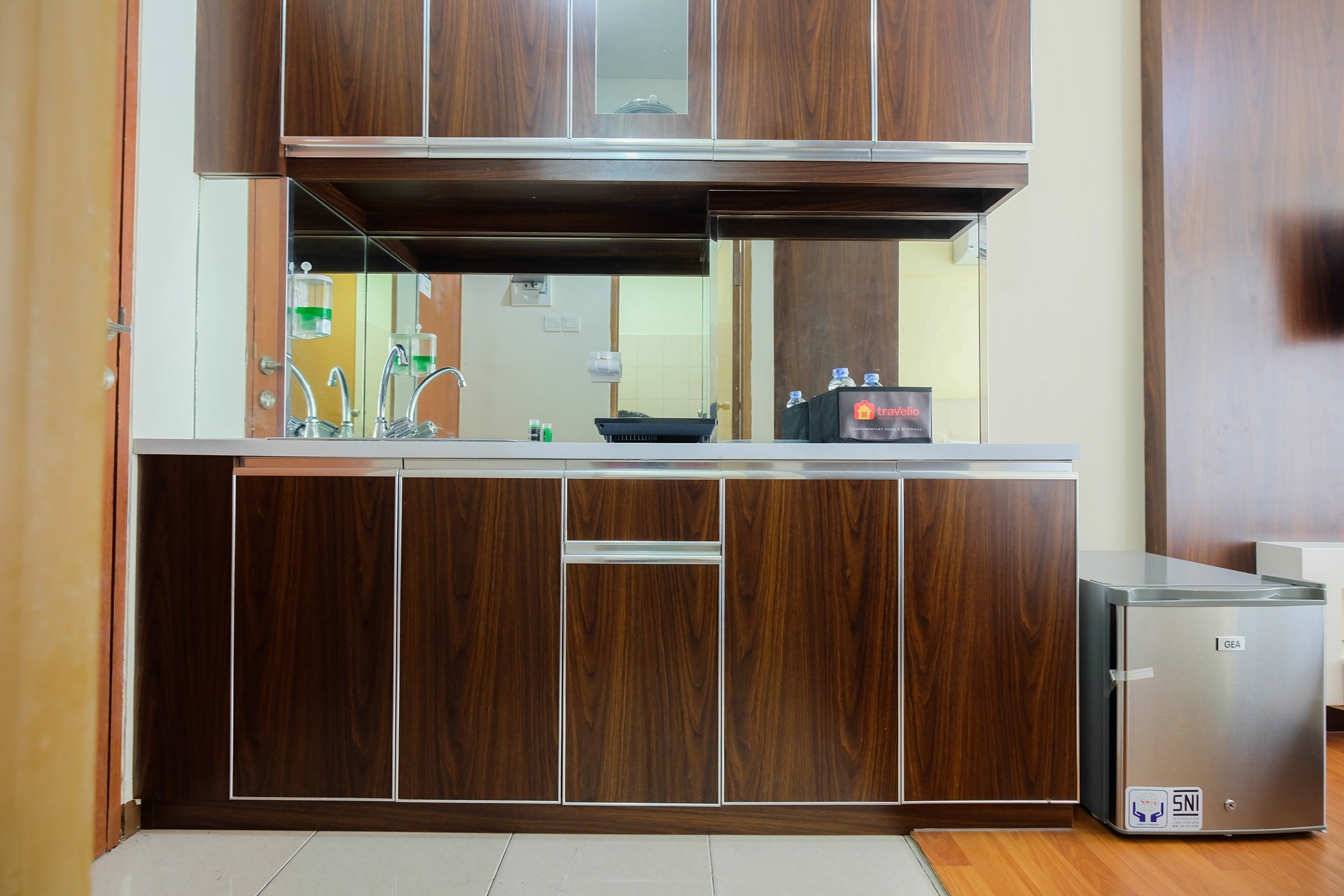A kitchen with wooden cabinets, a stainless steel refrigerator, and a sink.