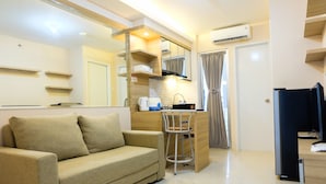 A modern living room with a sofa, a small dining table, and a kitchen area with a coffee machine. - Clean 2BR Bassura City Apartment (Jakarta)