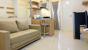 A modern hotel room with a sofa, a small kitchen area, and a bathroom. - Clean 2BR Bassura City Apartment (Jakarta)
