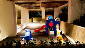 A children's play area with a slide and climbing structures. - Clean 2BR Bassura City Apartment (Jakarta)