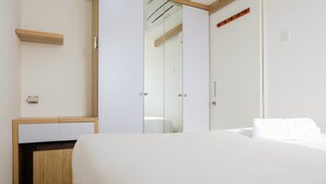 Ein modernes Hotelzimmer mit einem großen Bett, einem Nachttisch aus Holz, einem eingebauten Kleiderschrank und einer Duschkabine aus Glas.
