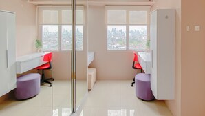 Un espacio de oficina moderno con dos escritorios, sillas y un ventanal que ofrece vistas a la ciudad.