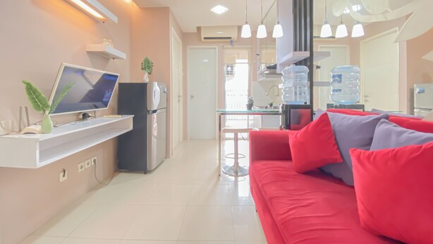 Una sala de estar moderna con un sofá rojo, un televisor de pantalla plana, una mesita y un dispensador de agua.
