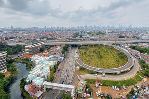 A cityscape with a prominent highway interchange, a river, and a mix of residential and commercial buildings. - Homey 1BR Apartment @ Bassura City (Jakarta)