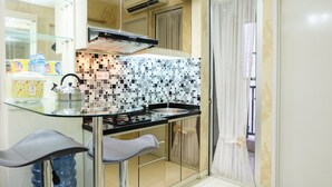Une cuisine compacte dotée d’un plan de travail en verre, d’une cuisinière noire et d’un pare-feu en carreaux.