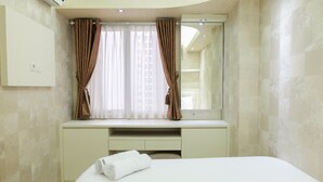 Une chambre d’hôtel comprenant un lit, une coiffeuse avec un miroir, une fenêtre avec des rideaux et un climatiseur fixé au mur.