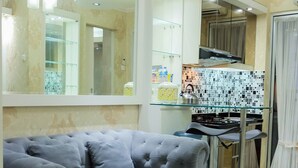 Un salon moderne avec un canapé gris, une table basse en verre et un coin bar équipé de tabourets.