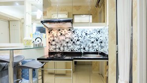 Une cuisine compacte dotée d’un plan de travail noir, d’un pare-feu en carreaux et d’un distributeur d’eau en verre.